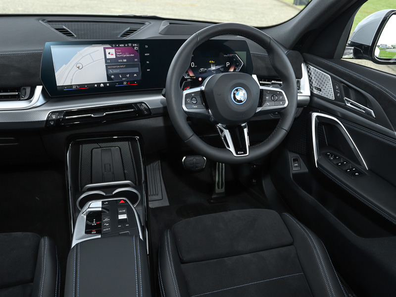 Inside BMW iX2 cockpit, showing steering wheel, infotainment screen, centre console etc.