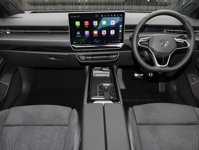 The VW ID.7's cockpit, showing the bottom of the driver and passenger seats, the dashboard, centre console and controls, infotainment screen, steering wheel and the bottom of the windscreen